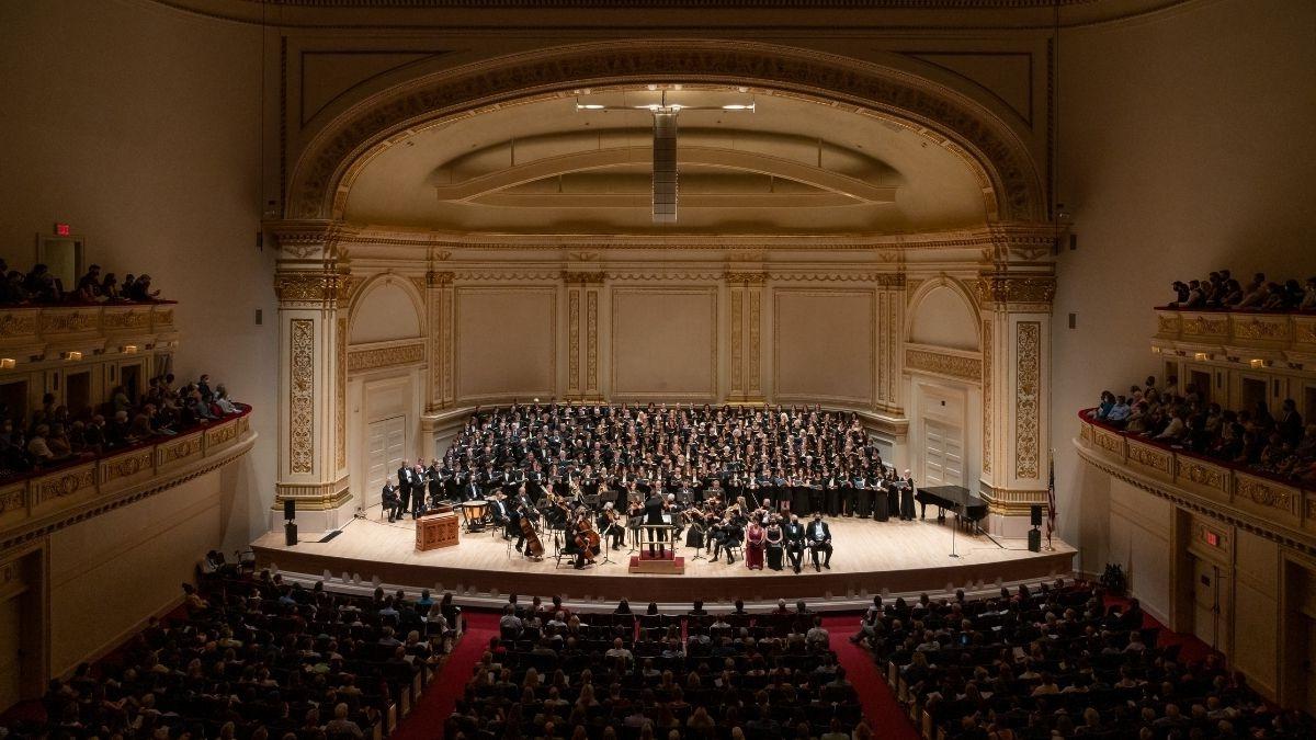 overhead view of carnegie hall with sold-out audience and choir and orchestra filling the stage